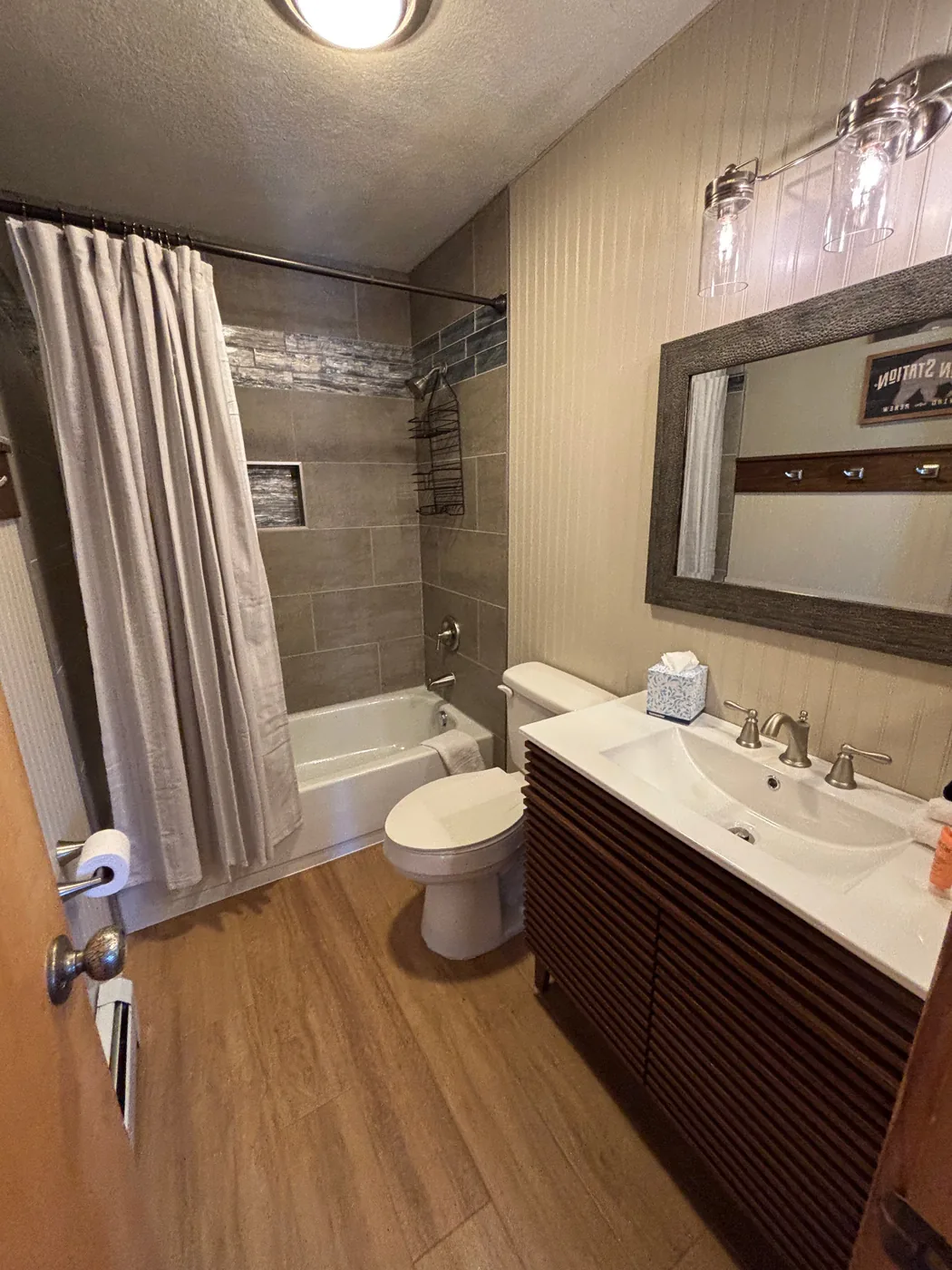 Updated bathroom with bathtub, shower curtain, vanity, mirror, and warm lighting