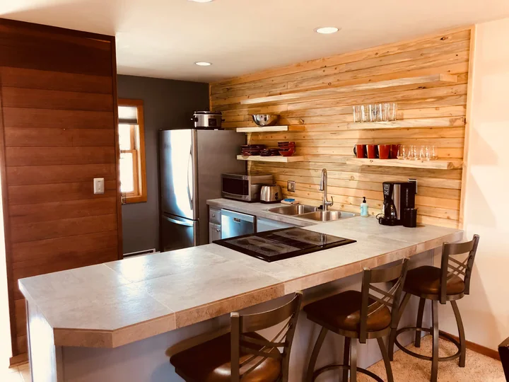Full kitchen with breakfast bar, refrigerator, microwave, dishwasher, coffee maker, and open shelving