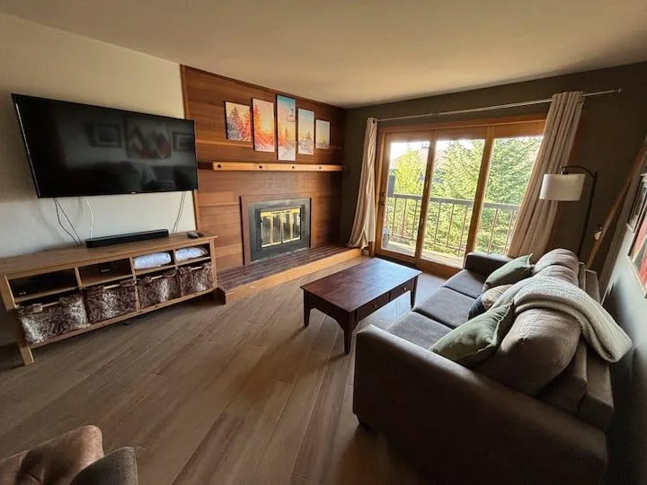 Living room with sofa sleeper area, fireplace, television, and balcony doors